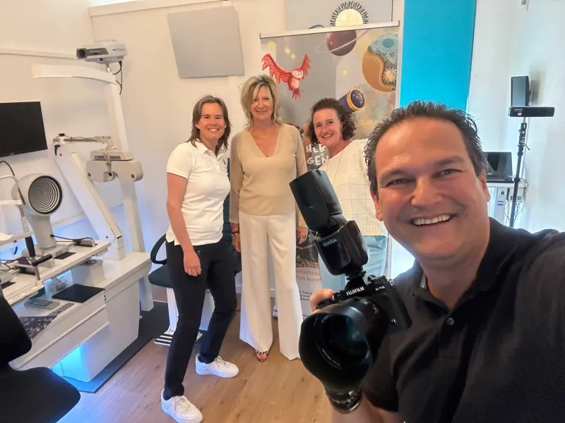 Fotograaf maakt met een videocamera een selfie met drie vrouwen in witte poloshirts in een praktijkruimte