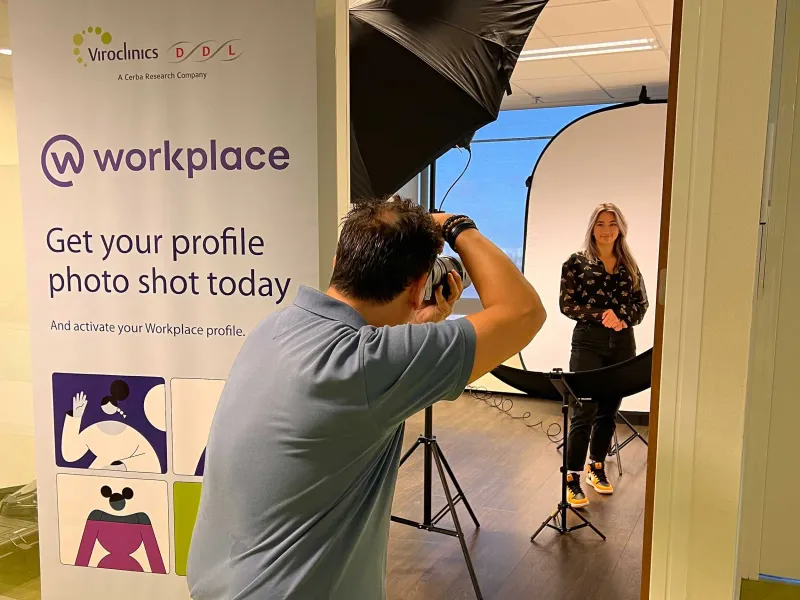 Fotograaf maakt een profielfoto van een vrouw bij een mobiele studio-opstelling op kantoor