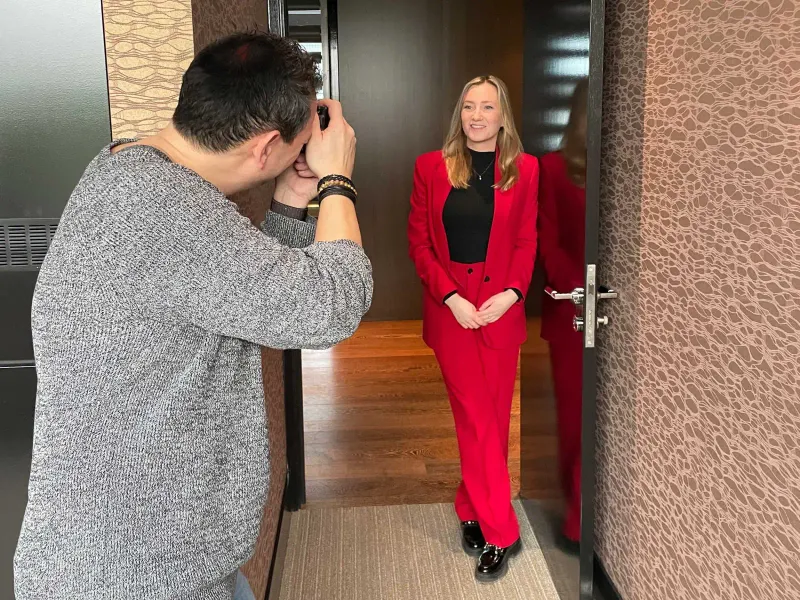 Fotograaf fotografeert een vrouw in een rood pak die in een deuropening staat
