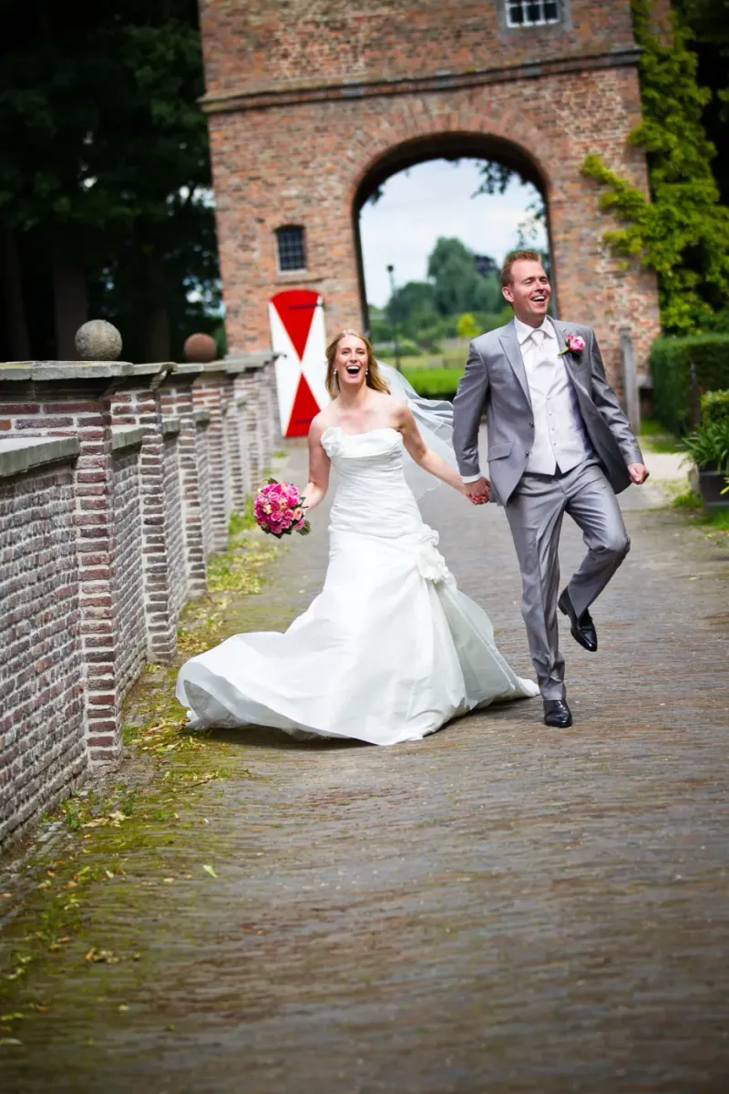 Bruidspaar loopt hand in hand door een historische stadspoort