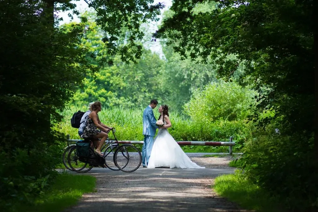 Het bruidspaar schittert in het midden van een natuurlijke omlijsting van bomen en struiken.