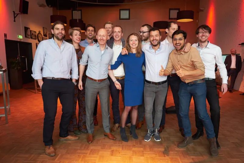 Grote groep jonge professionals poseert arm in arm op een bedrijfsfeest