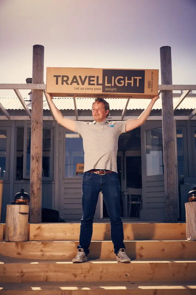 Man hangt speels aan een houten constructie met het opschrift Travel Light