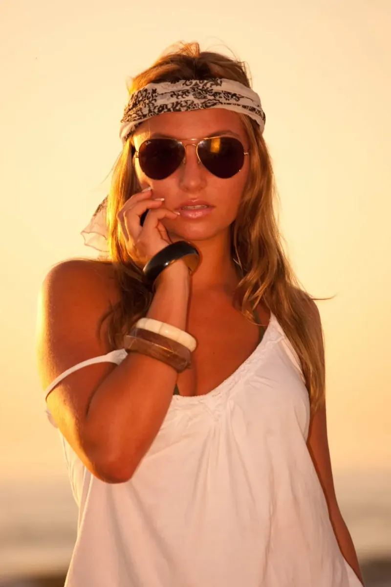 Modeportret bij avondlicht van een vrouw met zonnebril en armbanden