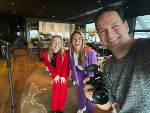 Stefan met 2 casting modellen: drie mensen lachen naar de camera in een restaurant, de fotograaf houdt een camera vast.