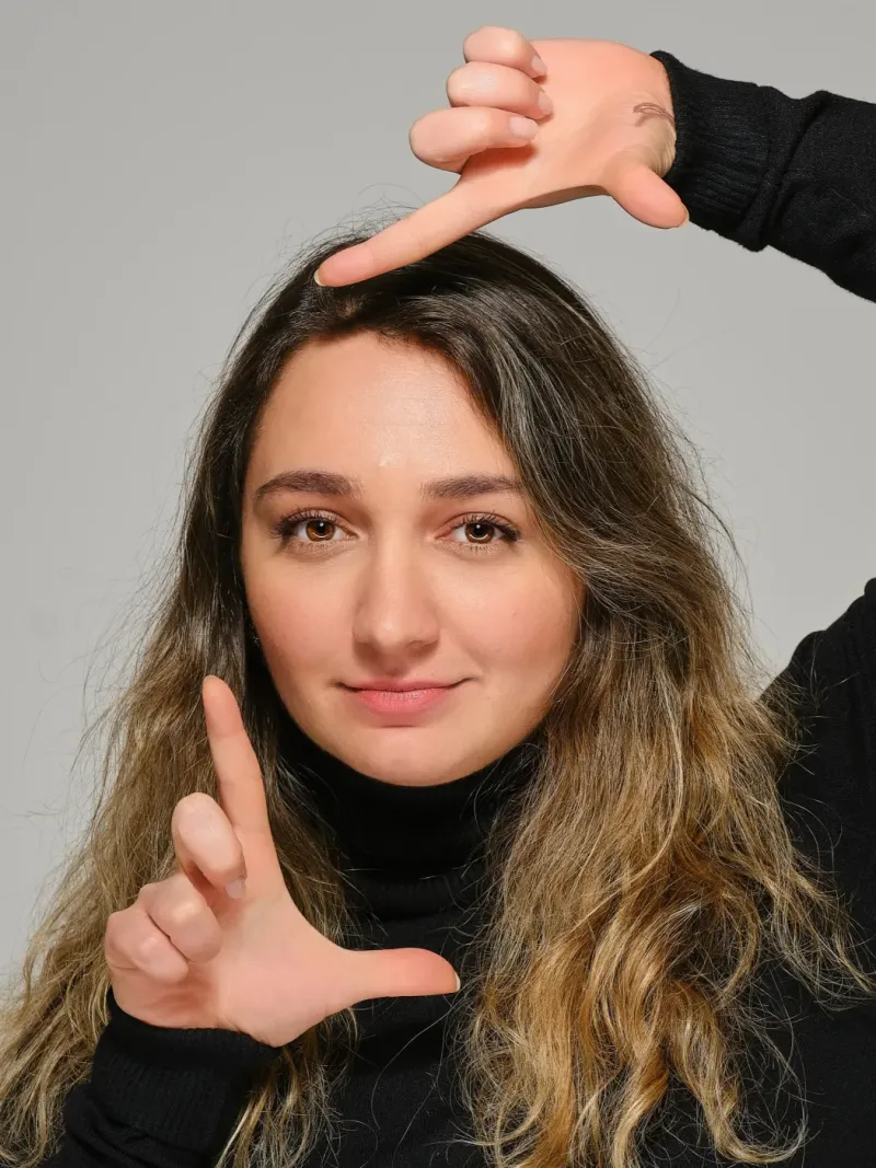 Portret van een vrouw die met haar hand een kader om haar gezicht maakt