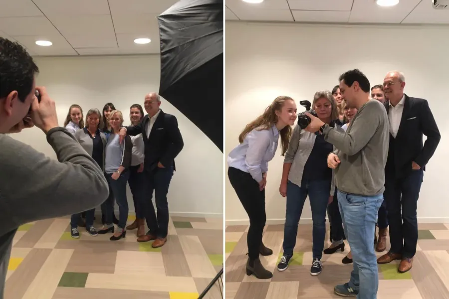 Groep mensen poseert voor de camera in een lichte kamer, in een fotoshoot setting met een professionele fotograaf en studioverlichting.