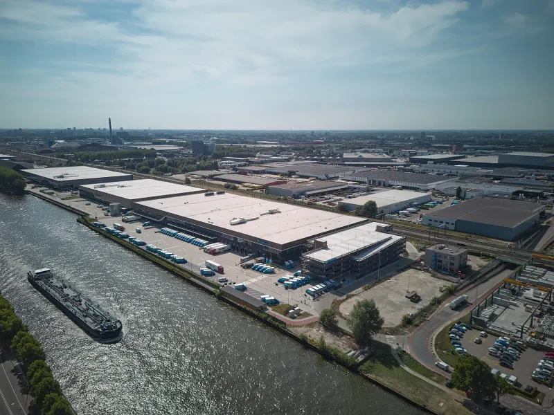 Luchtfoto van een bedrijventerrein langs een kanaal met een passerend vrachtschip