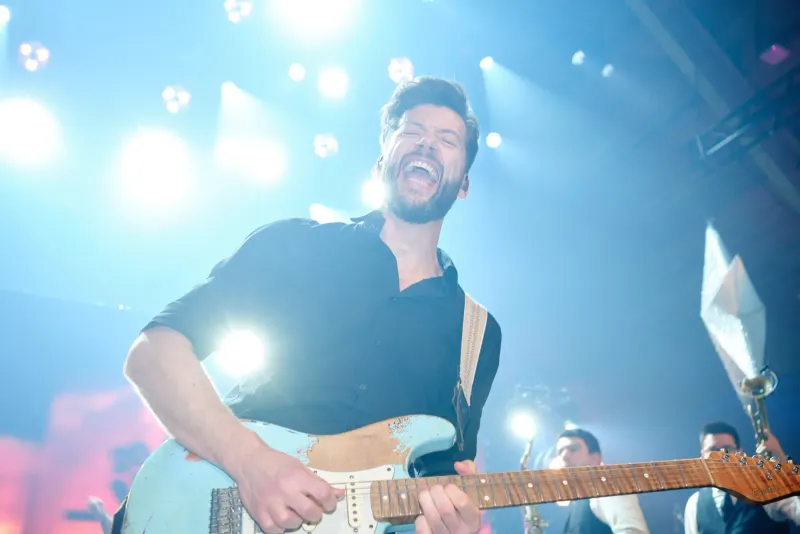Zanger met gitaar treedt uitbundig op onder blauwe podiumverlichting