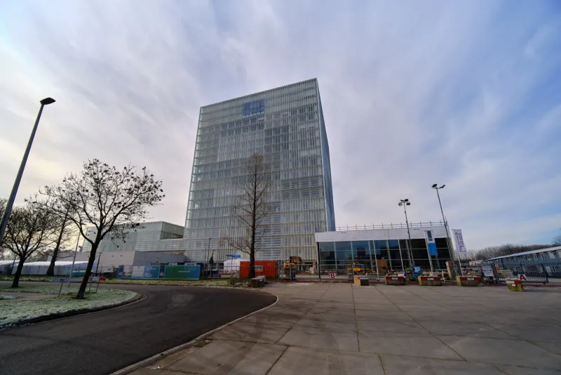 Modern kantoorgebouw langs een lege weg onder een weidse bewolkte lucht