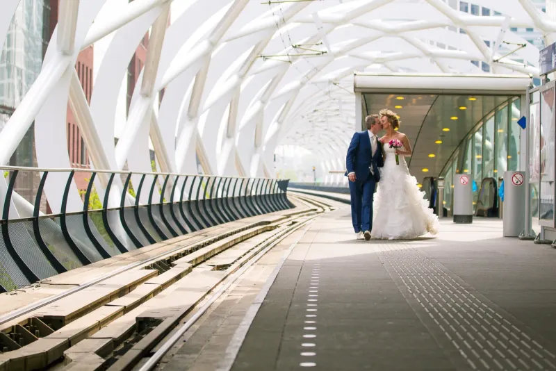Bruidspaar omhelst elkaar in de witte vakwerktunnel van een tramstation