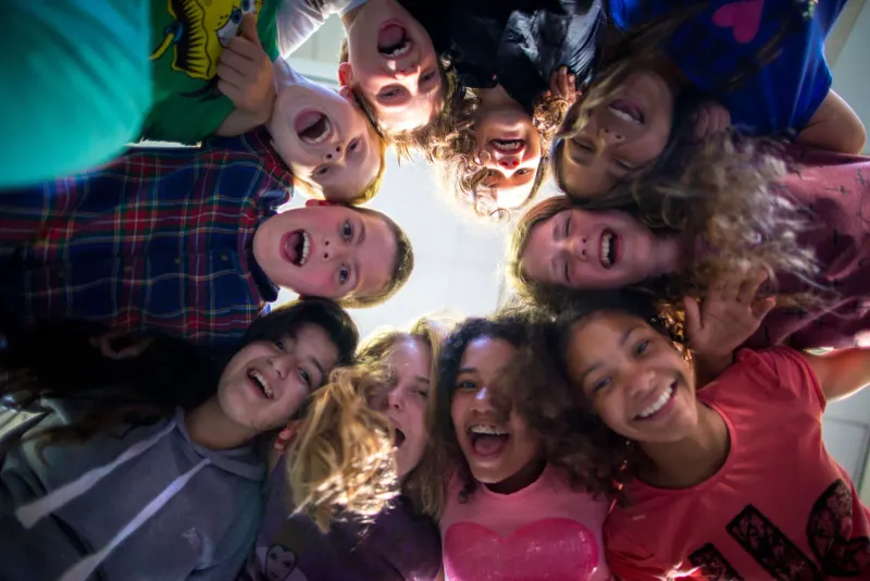 Kinderen met de hoofden bij elkaar kijken lachend omlaag in de camera