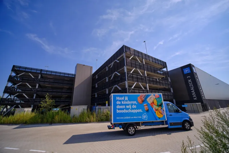 Grote parkeergarage met een blauwe bezorgbus geparkeerd ervoor