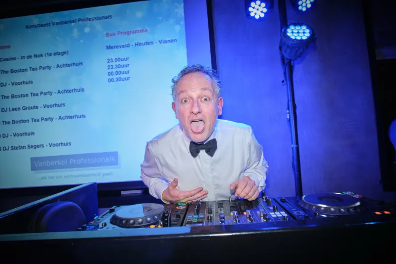 Dj in smoking achter draaitafels met blauw licht en een geprojecteerde speellijst
