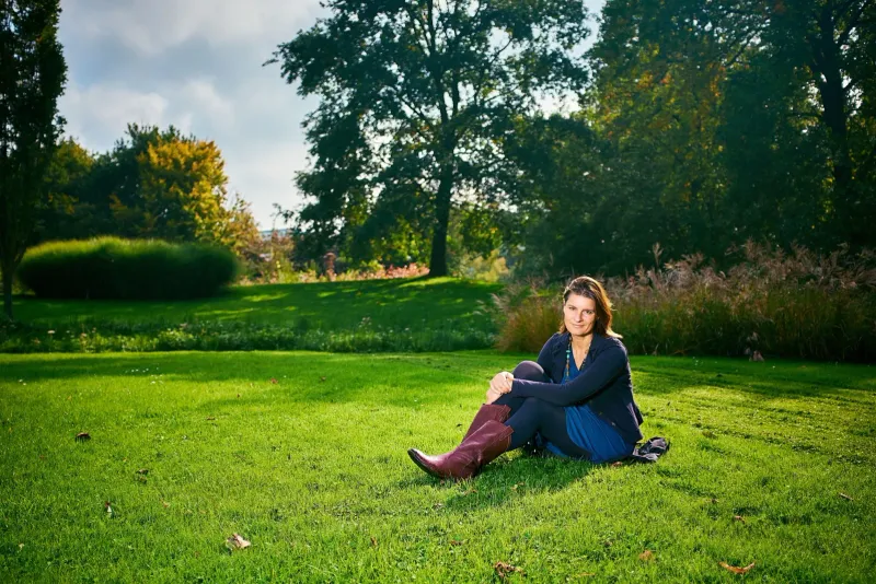 Vrouw in blazer zit ontspannen in het gras in een groen park