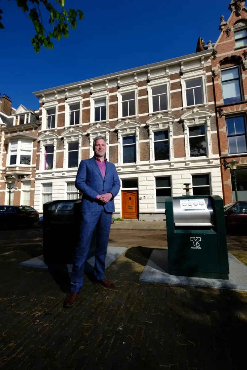 Man in een blauw pak in een smalle straat met hoge gevels, van bovenaf gefotografeerd